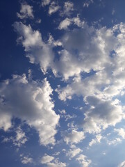 Blue illuminated radiant bright cloudy sunny sky with fluffy clouds in variety of shapes, atmospheric beautiful cloudscape.