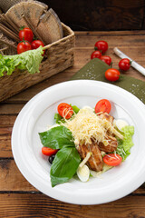 Salad with cherry tomatoes, grated cheese and lettuce on a wooden background
