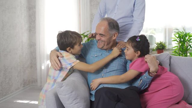 Happy family picture. Grandchildren hug their sad grandfather.
The grandchildren run and hug their grandparents and the grandpa is happy.
