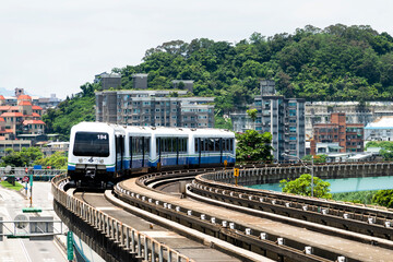Naklejka premium Wenhu or Brown line of Taipei MRT in Taiwan. the train running on elevated rails of the Taipei Metro System between buildings under the clear blue sky.