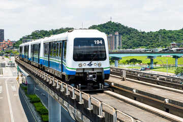 Fototapeta premium Wenhu or Brown line of Taipei MRT in Taiwan. View of a train running on the elevated track of the Taipei subway system under a clear blue sky.