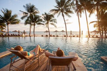honeymoon couple relaxing in beach hotel near swimming pool at sunset, dream holidays