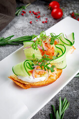 Delicious snacks. Bruschetta with salmon, sliced fresh cucumber, red onion rings and arugula. Toasted croutons with seafood and lettuce