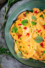 Italian Cuisine. Round ravioli with stuffing and pesto sauce. Pasta egg yolk raviolo