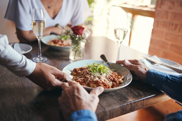 Food service, wine and couple at table with hospitality from waiter at restaurant for lunch. Cafe worker with plate of pasta for man and woman on date for anniversary or marriage at fine dining cafe