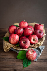 Ripe apples in basket on wooden table, front view, dark background with copy space