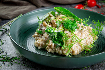 Ptitim with mushrooms and cream sauce and green spinach leaves in a plate