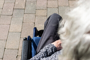 Elderly lady in a wheelchair in the sun in the park
