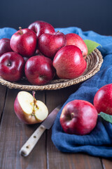 Ripe apples in basket on wooden table with blue napkin, front view, dark background, selective focus