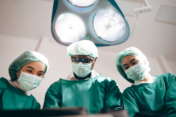 Group of concentrated surgeons team engaging in rescue of male patient in hospital operation room, emergency case of surgery medical technology, health care and disease treatment concept