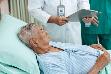 Obraz premium professional doctor standing by explain the treatment information via male elderly patient lying in bed in private hospital sickroom. The treatment program is suitable for people to socialize elderly