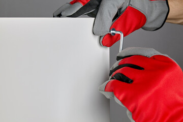 Hands in red gloves twist the confirmation with a hex key
