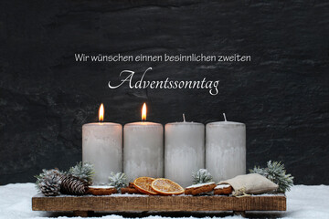 Dekoration zum zweiten Advent. Zwei brennende Kerzen mit Zimtsternen, Orangenscheiben und...