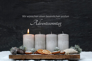 Dekoration zum ersten Advent eine brennende Kerzen mit Zimtsternen, Orangenscheiben und...