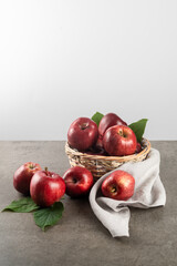Ripe apples in basket on stone table with gray napkin, front view, white background, copy space