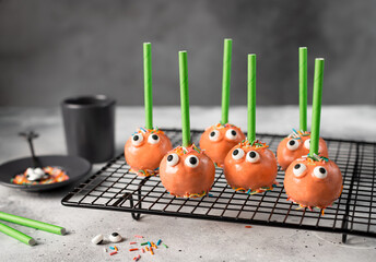 Festive pumpkin cake pops with funny faces on dark background. Halloween treats. copy space