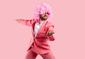 Funny bearded man in wig, glasses and suit having fun isolated on pink background. Caucasian man in...