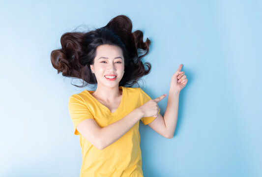 Image of young Asian woman lying on background