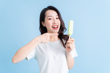 Young Asian woman eating ice cream on background