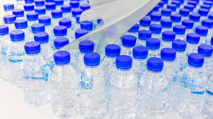 Lots of water bottles. Bottles with blue caps. Bottling plant-Water bottling line for processing and bottling drink water into bottles.