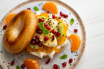 Toasted bagel with orange marmalade, cream cheese, tangerine, kiwi, banana and pomegranate. vegan breakfast. Superfood vegan brunch.