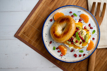 Toasted bagel with orange marmalade, cream cheese, tangerine, kiwi, banana and pomegranate. vegan breakfast. Superfood vegan brunch.