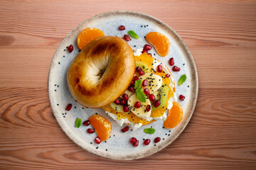 Toasted bagel with orange marmalade, cream cheese, tangerine, kiwi, banana and pomegranate. vegan breakfast. Superfood vegan brunch.