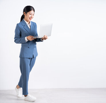 Full length image of young Asian businesswoman holding laptop