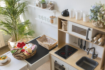Cute little baby boy in chef hat and apron playing at childish kitchen cooking food back view