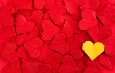 Yellow origami heart on red origami hearts