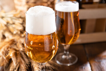. Glass of light craft beer on a wooden table. Beer is poured into a glass with foam and bubbles. Vertical. for social media or advertising. beer texture. Copy space