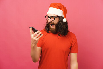 Mad bearded man wearing Christmas cap is screaming at his phone in a studio.