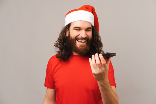 Happy young man is talking on speaker with family on the phone at Christmas.