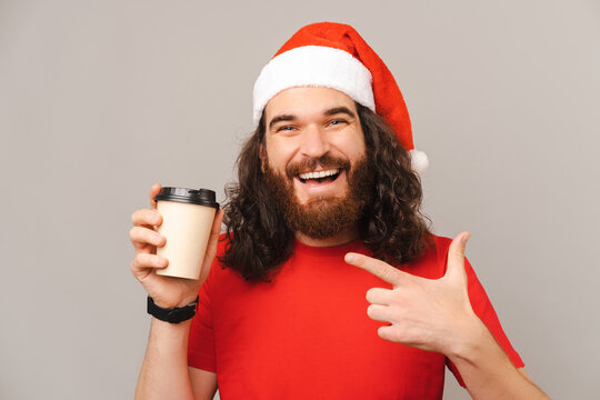 Ecstatic man points at the to go cup he is holds and wearing a Christmas cap.