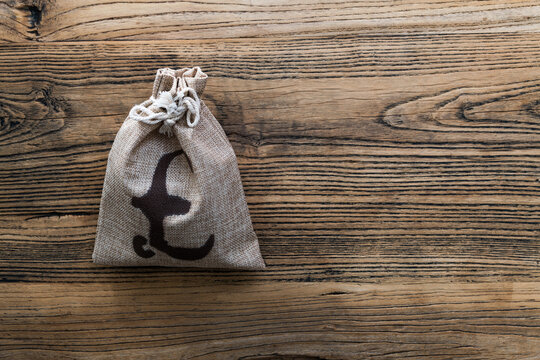 Money bag with pound sign on wooden table