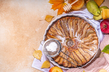 Homemade pear pie, sponge cake with sliced pear, cinnamon and honey, with fresh pears on beige stone background top view copy space