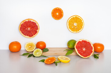 Wooden empty podium or pedestal for presentation of beauty products with citrus extracts. Sliced ​​fresh orange, grapefruit, lime and tangerine nearby. Advertising of natural vitamin cosmetics