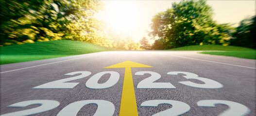 Road into evening sunrise with the numbers 2023 ahead on asphalt - 3D illustration