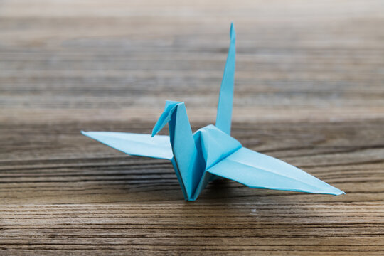 Blue origami paper crane on wooden table