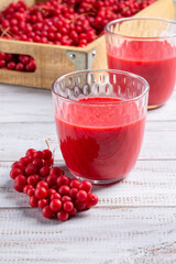 Schisandra berry juice in glass on white wooden background.
