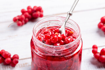 Schisandra chinensis jam on white wooden table. Five-flavor berries with sugar in a glass jar