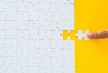 Hand putting the last piece of white jigsaw puzzle