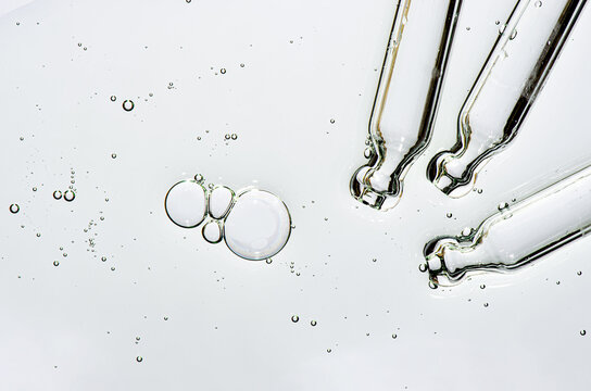 Three pipettes and a serum texture for skin with bubbles. Liquid body care product. Close-up.
