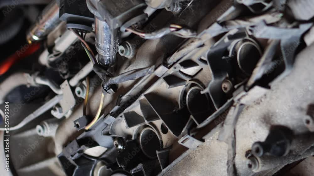 Poster vertical video format of auto mechanic removing spark plugs from car engine