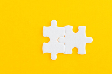 Obraz premium Two puzzle pieces on yellow background
