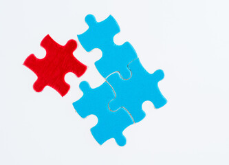 Three blue and one red puzzle pieces on white background