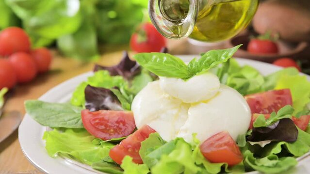 Salad with Tomatoes, Burrata, basil,olive oil. middle name Burratina. Traditional cheese from the south of Italy in the Puglia region. Round soft cheese inside liquid stracciatella texture 