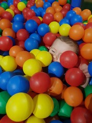 Fototapeta na wymiar white baby boy playing with colourful balls ball pool 