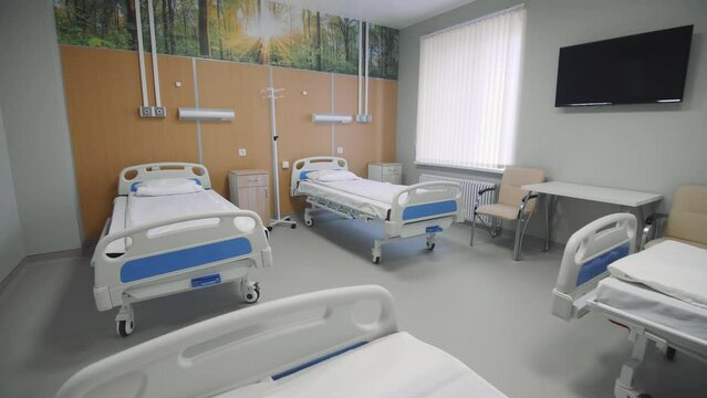 Contemporary wheeled beds with pillows and blankets in spacious hospital ward. Patient service at medical center