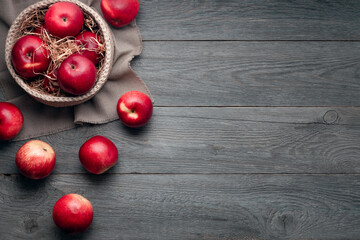 ripe big red apples in a basket on an old wooden background, free space, top view